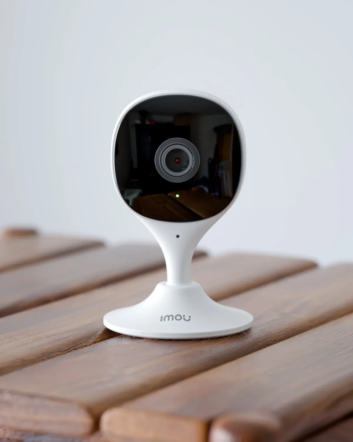 La caméra Imou Cue 2C posée sur une table en bois, voyant vert allumé